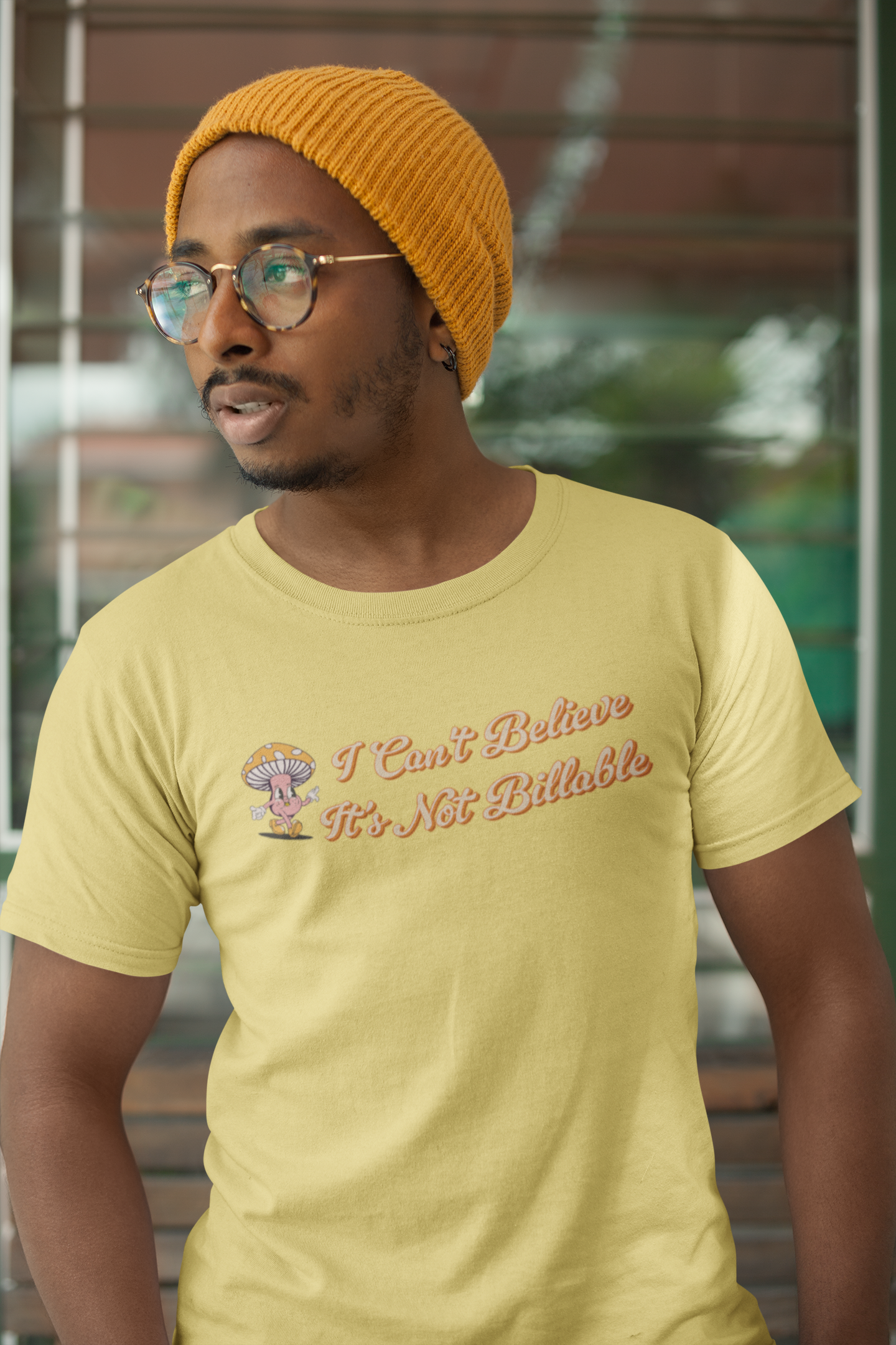 I Can't Believe It's Not Billable 100% Organic Cotton Tee Man wearing a yellow t-shirt with text and a graphic, standing outdoors.