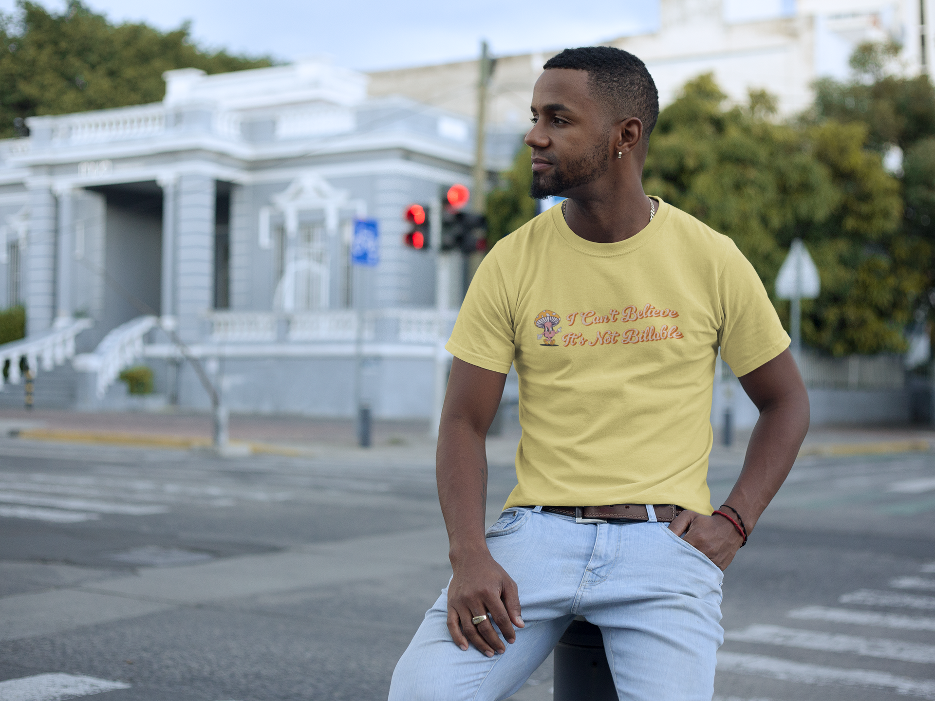 I Can't Believe It's Not Billable 100% Organic Cotton Tee Man wearing a yellow t-shirt  with text, standing on a street corner.