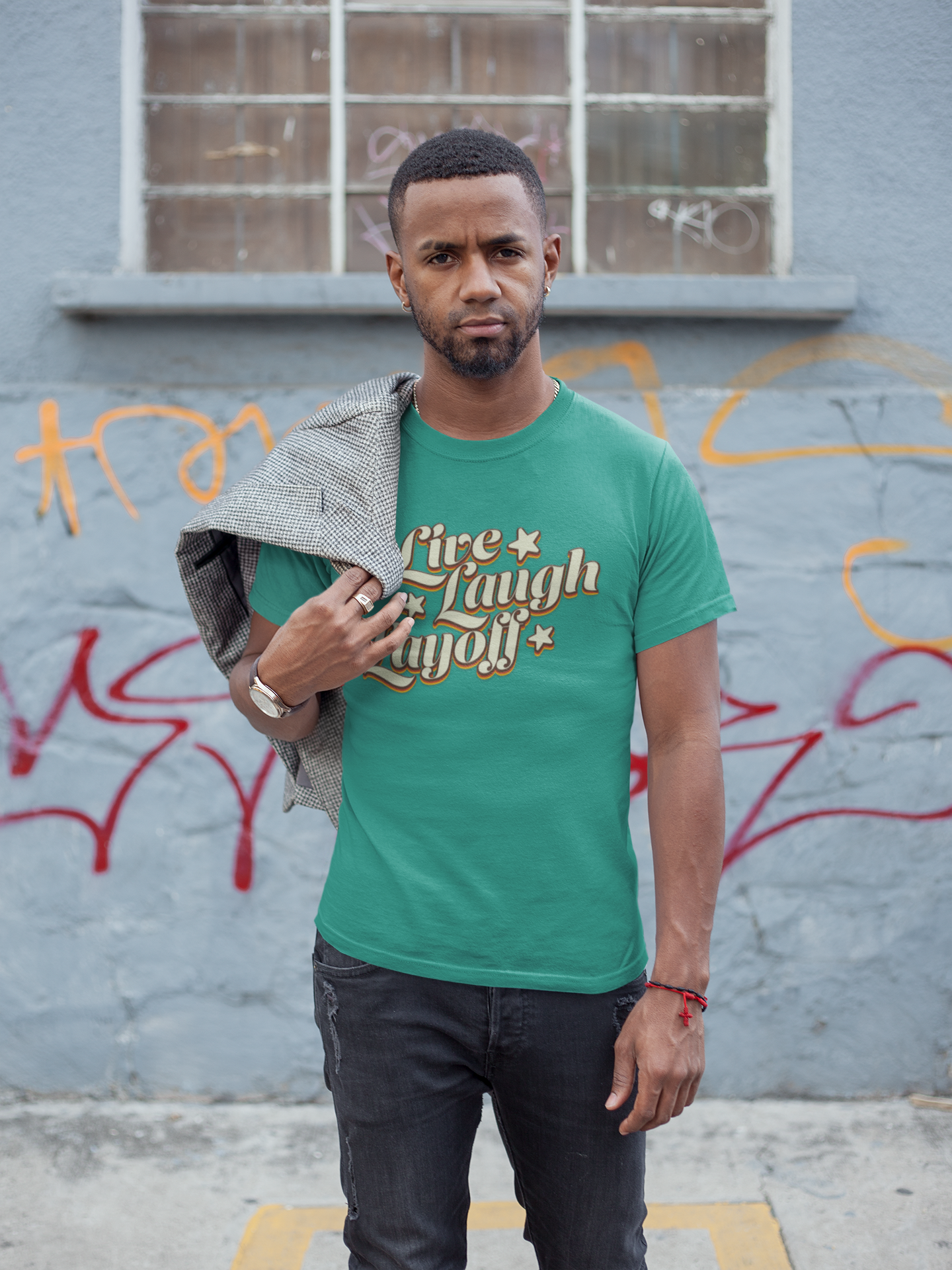 Live Love Layoff Humorous TShirt Man wearing a green t-shirt with text standing against a graffiti-covered wall.