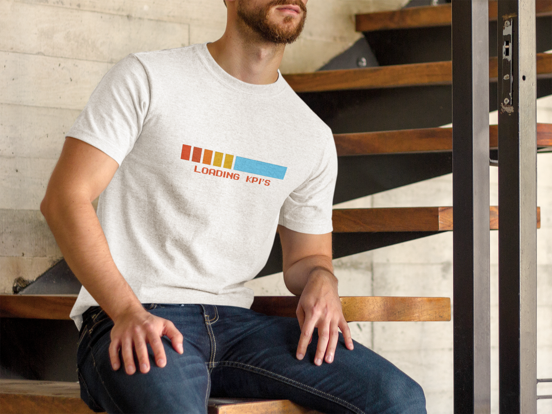 Loading KPI's Humourous T-Shirt Person wearing a white t-shirt with colorful text design sitting on stairs.