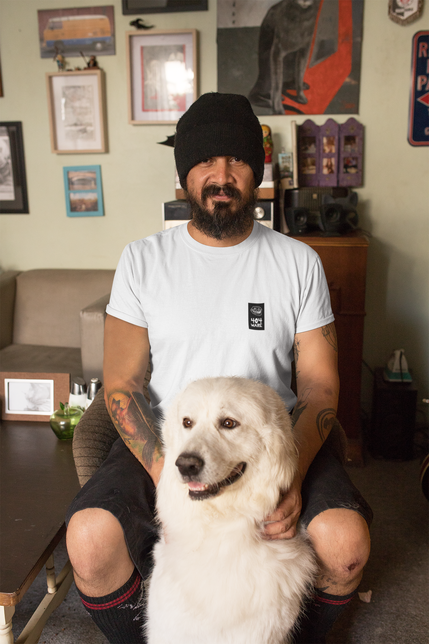 Organic Cotton T-Shirt 404 Troll Man sitting with a white dog in a room with various items on the wall.