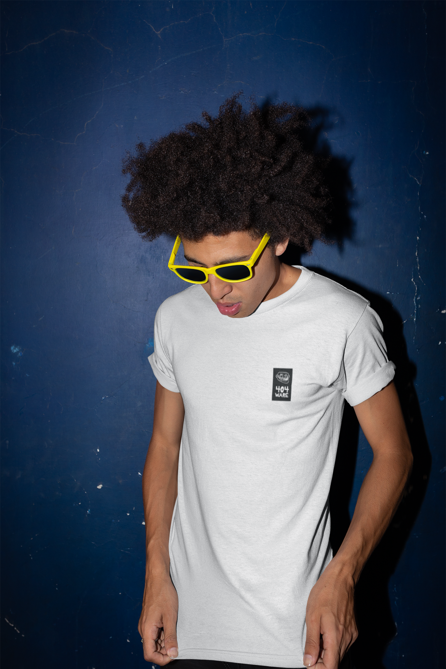 Organic Cotton T-Shirt 404 Troll Person wearing a white t-shirt with a small logo, yellow sunglasses, and dark hair against a blue background.