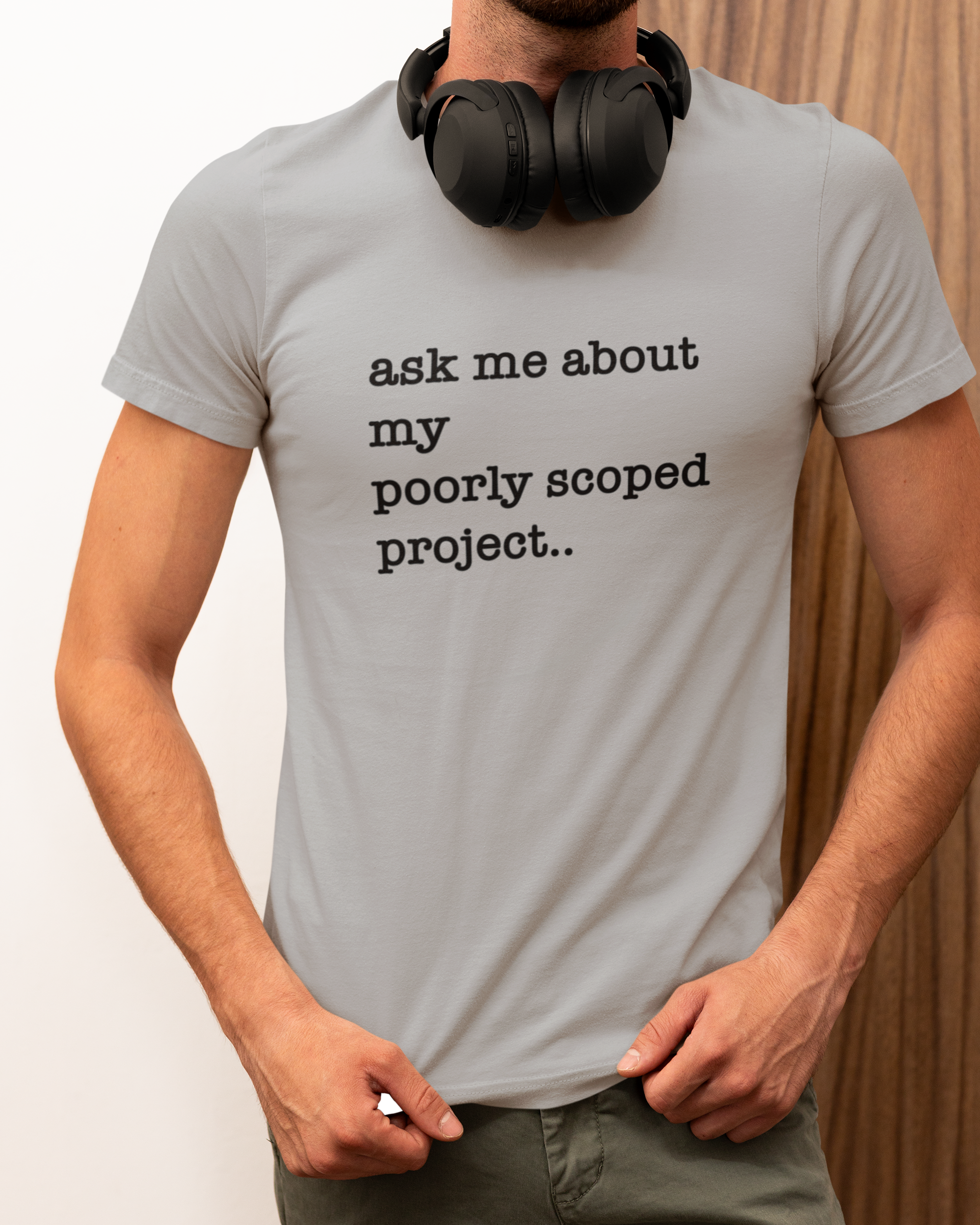 Organic Cotton Tee: Ask Me About My Poorly Scoped Project Person wearing a gray t-shirt with text and headphones, standing against a neutral background