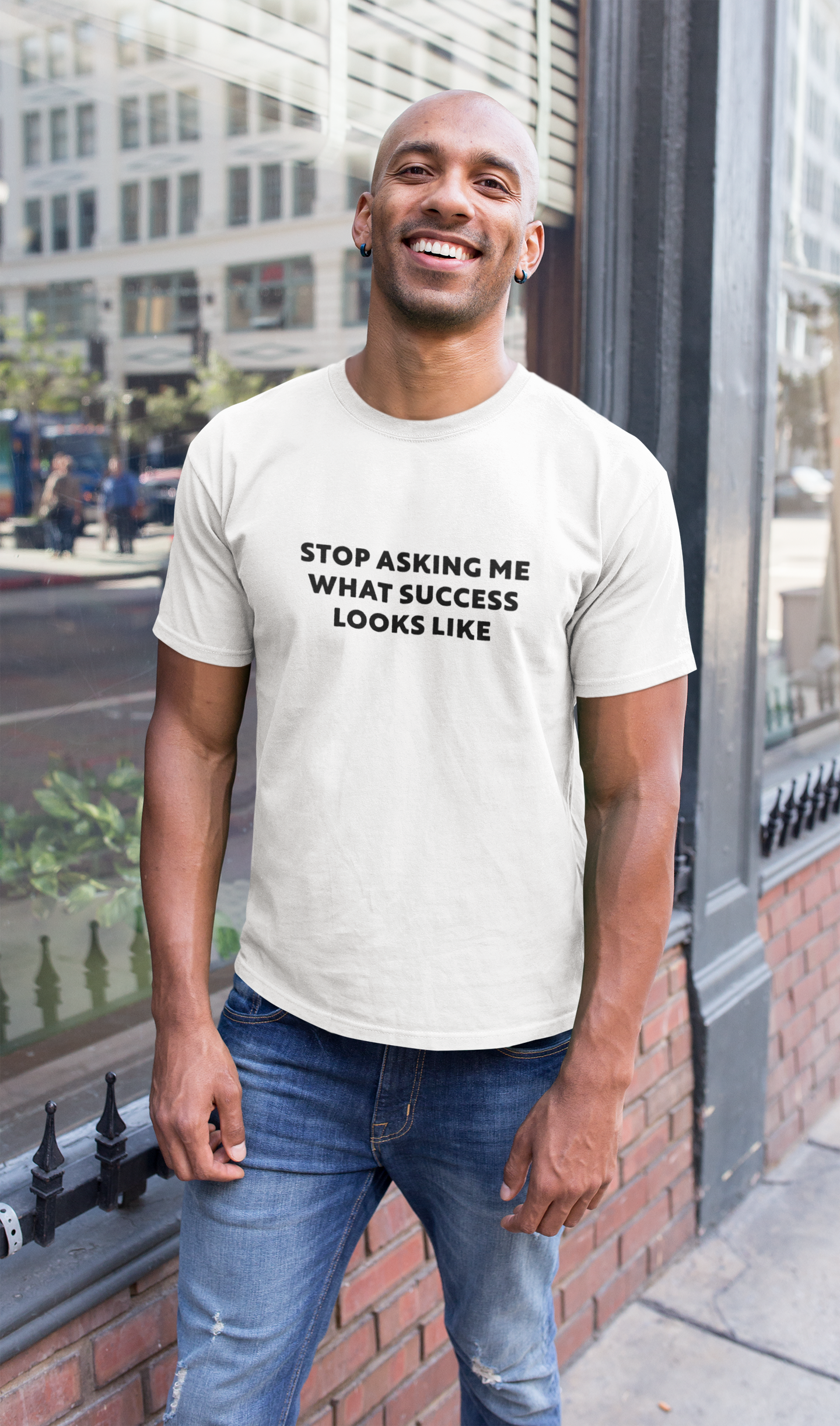Stop Asking What Success Looks Like  T-Shirt  Man wearing a white t-shirt with text standing on a city street.