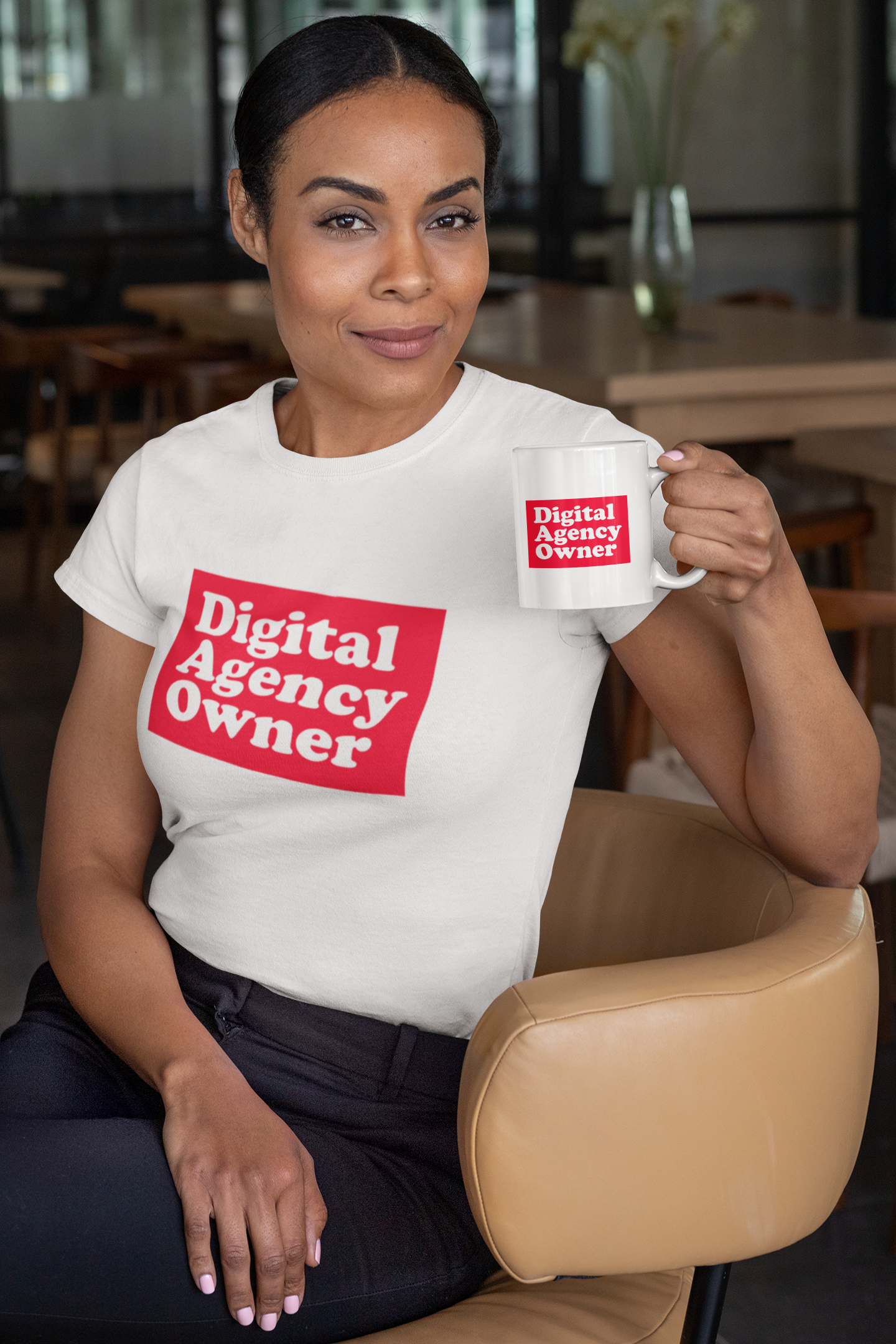 Woman wearing a white t-shirt with 'Digital Agency Owner' text, holding a matching mug in a casual setting.