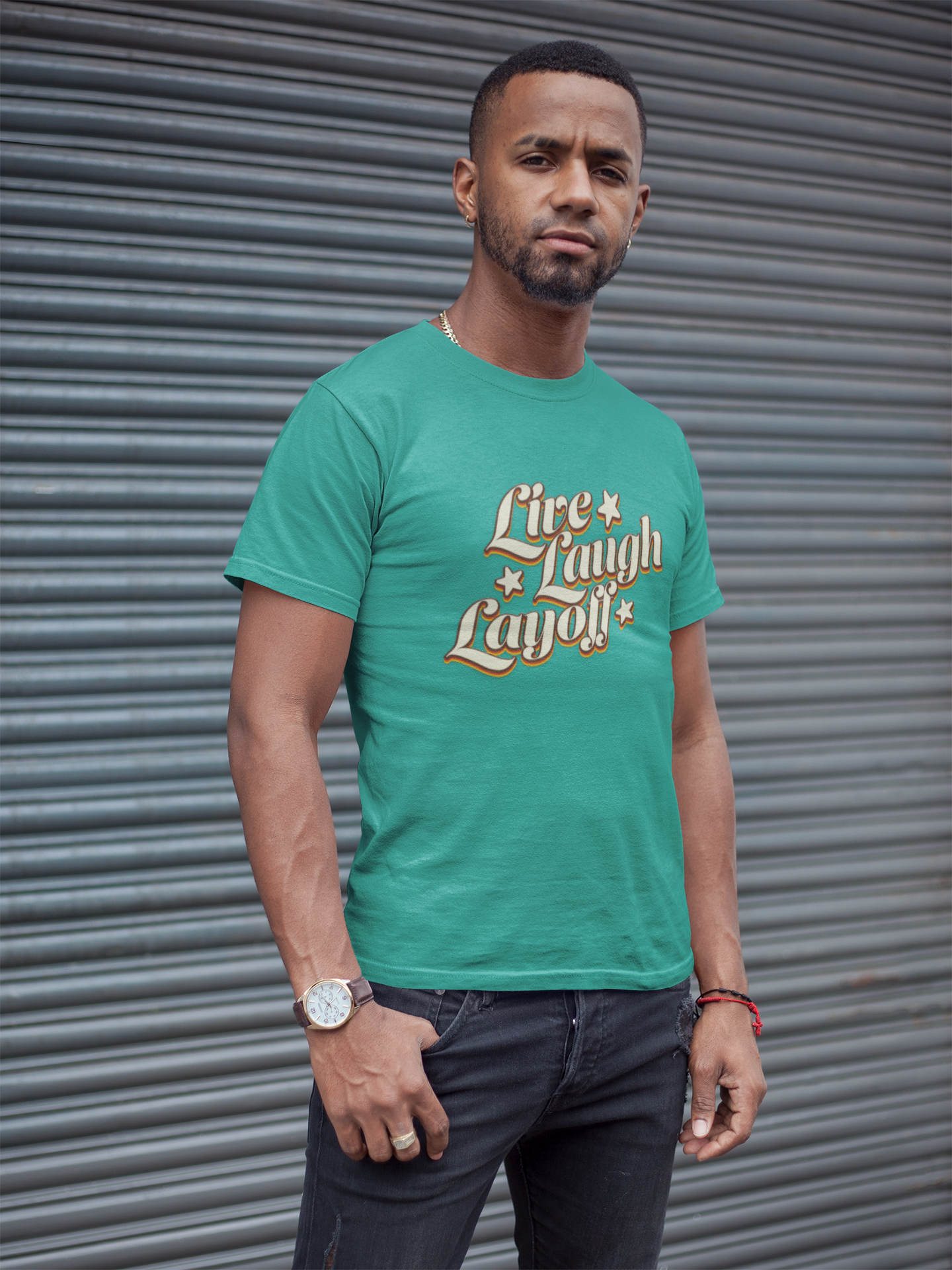 Live Love Layoff Humorous TShirt Man wearing a teal t-shirt with text standing in front of a metallic shutter.