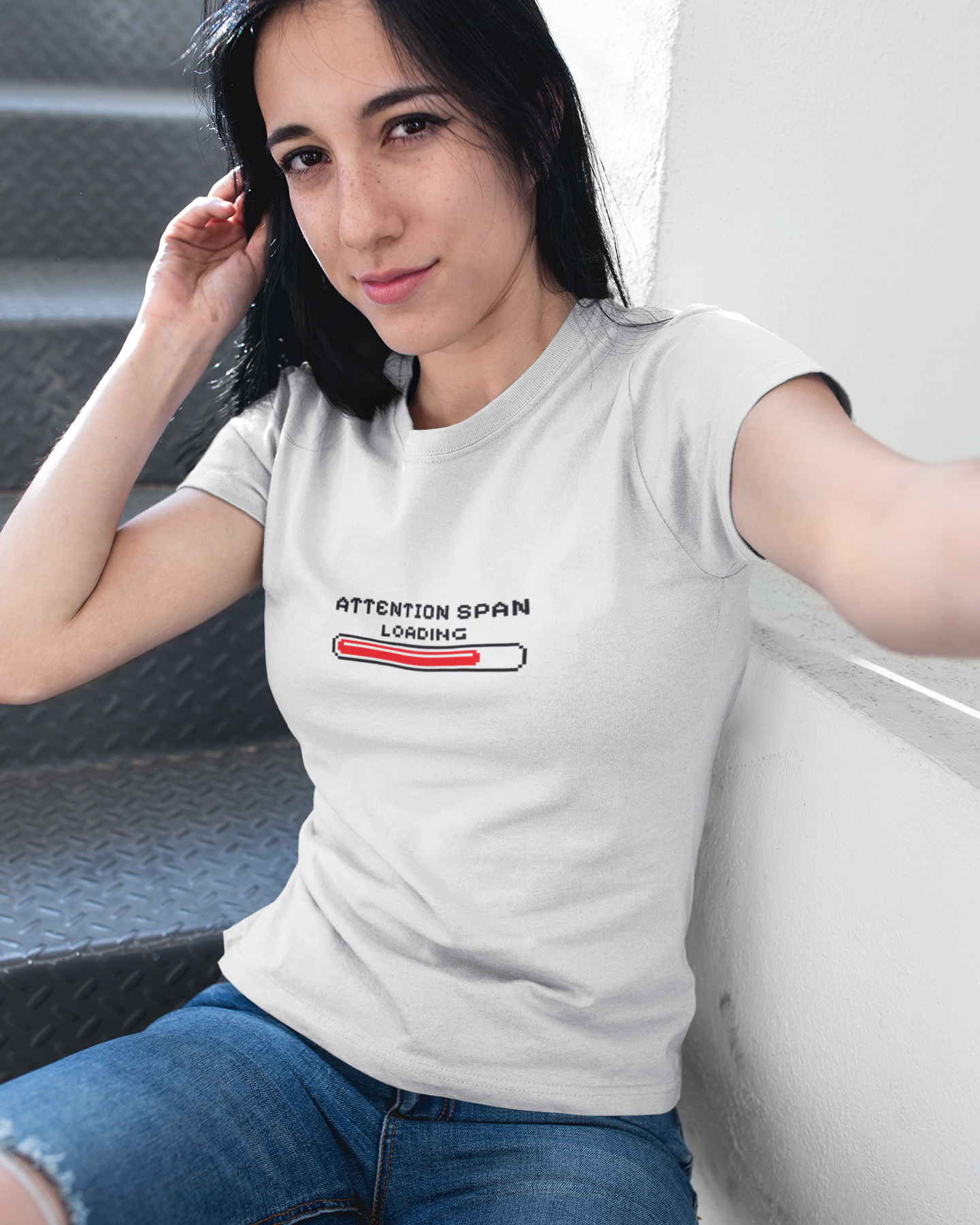 Woman wearing a white t-shirt with text and graphics, sitting on a couch.