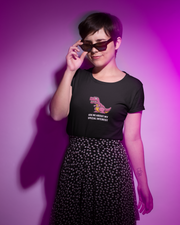 Person wearing a black t-shirt with a graphic and text, standing against a purple background