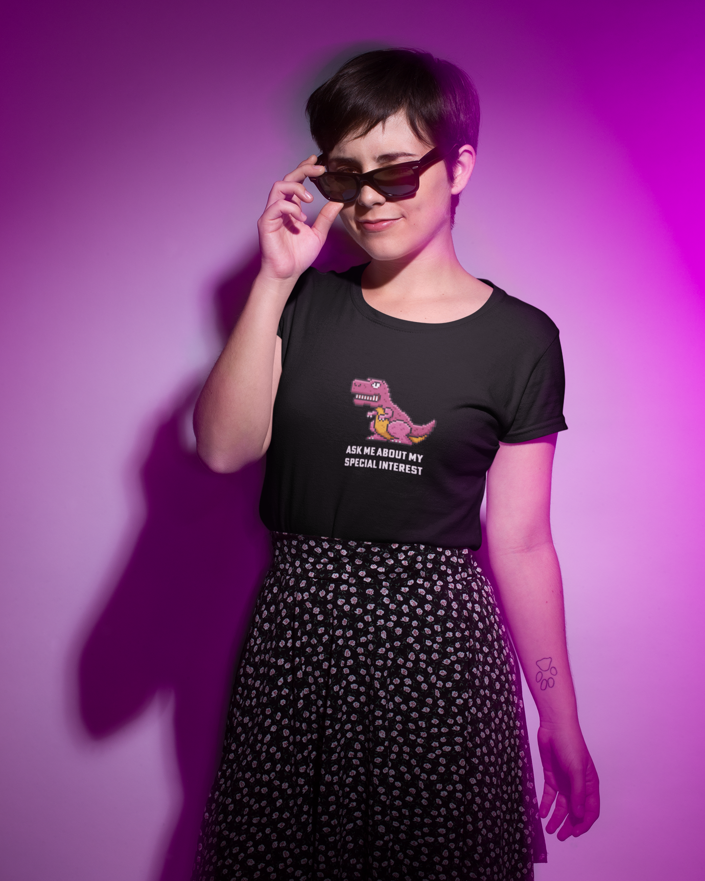 Person wearing a black t-shirt with a graphic and text, standing against a purple background