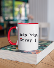 Mug with 'hip hip, array[]' text on a stack of books with a blurred background
