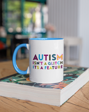 Mug with 'Autism isn't a glitch, it's a feature' text on a stack of books.