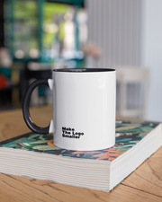 White mug with black handle on a stack of books in a blurred indoor setting