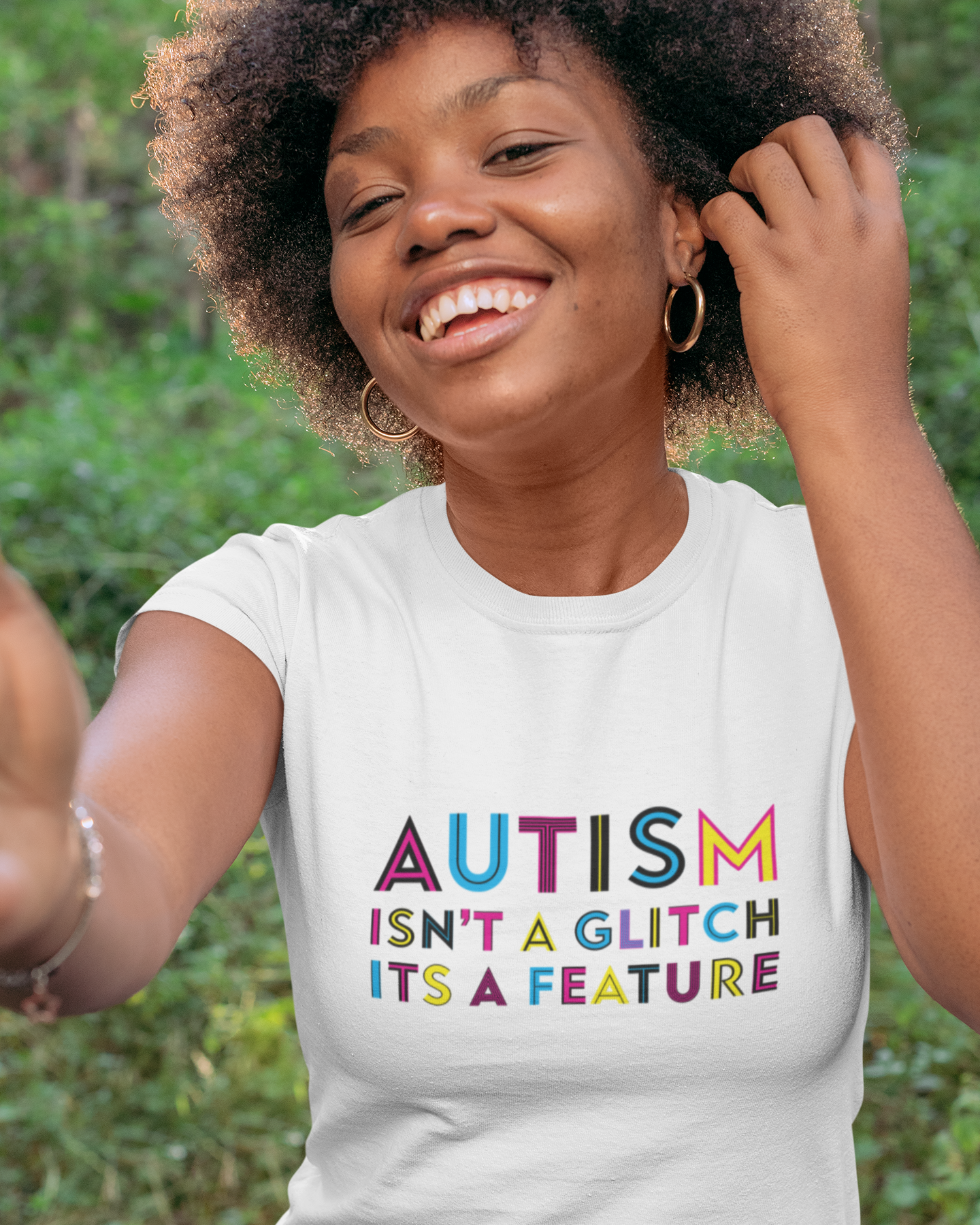 Person wearing a white t-shirt with 'Autism isn't a glitch, it's a feature' text outdoors.