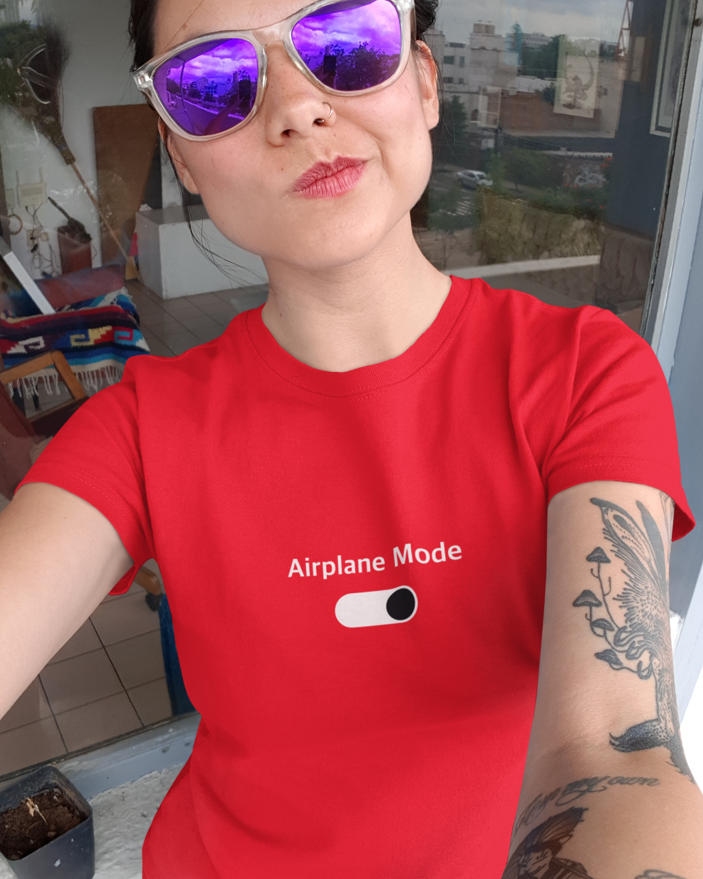 Person wearing a red t-shirt with 'Airplane Mode' text and a toggle graphic, indoors.